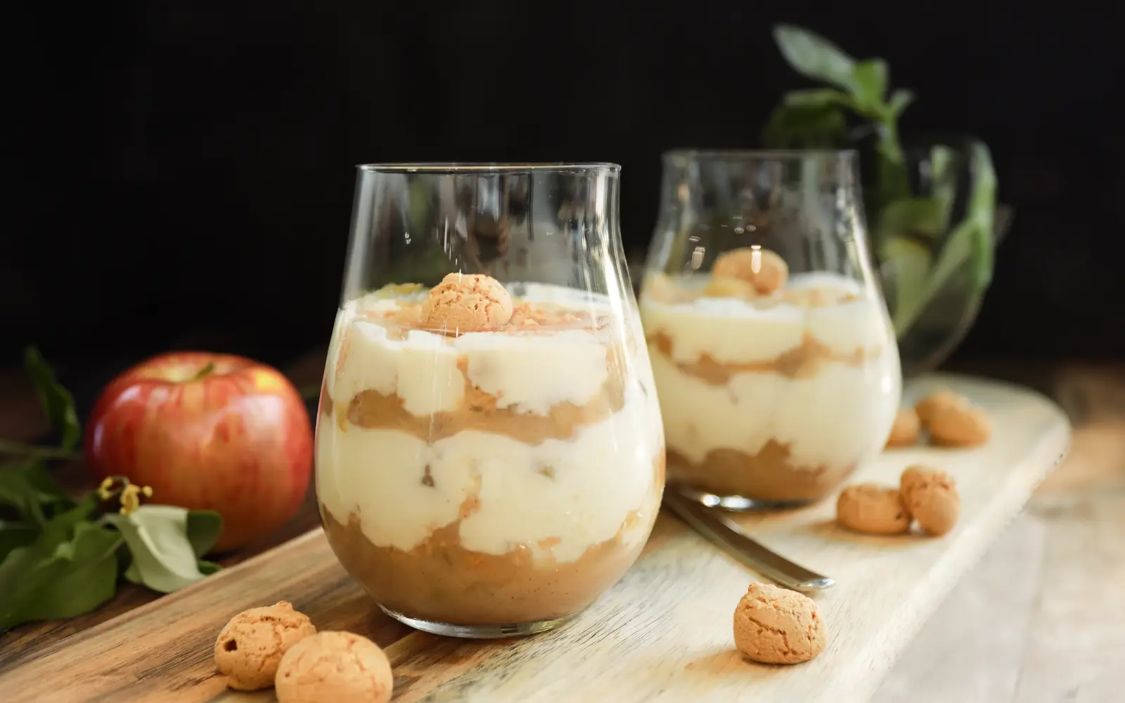 Apfel Quark Dessert 2 Glaeser auf einem Holzbrett mit einem Apfel Im Hintergrund