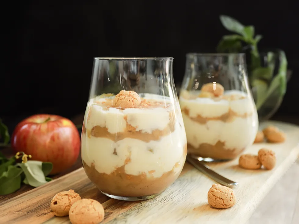 Apfel Quark Dessert 2 Glaeser auf einem Holzbrett mit einem Apfel Im Hintergrund