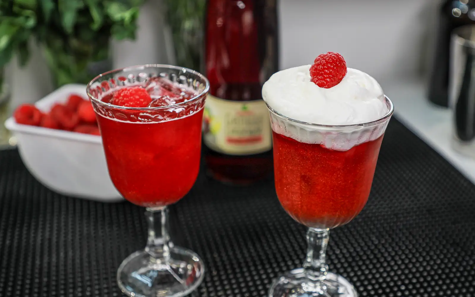 vorderansicht einer Teinacher 1 Liter Genussflasche und 2 Gläser gefüllt mit Kirsch-Zitrone mit Himbeeren