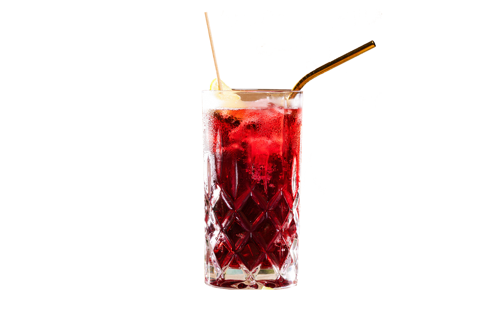 teinacher-blog-mocktail-magie-schritt-07-das-richtige-glas-fuer-den-job Hoher Kristallglas-Mocktail in tiefroter Farbe mit Eiswürfeln, Zitronenscheibe und goldenem Strohhalm.