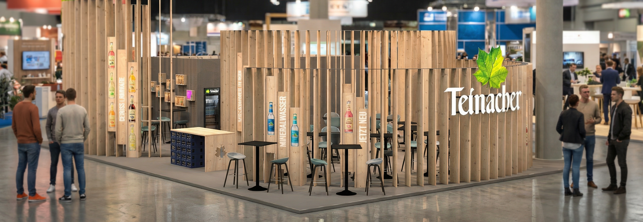 Moderner Teinacher-Messestand aus Holz mit Sitzbereichen und Produktpräsentation in einer Messehalle