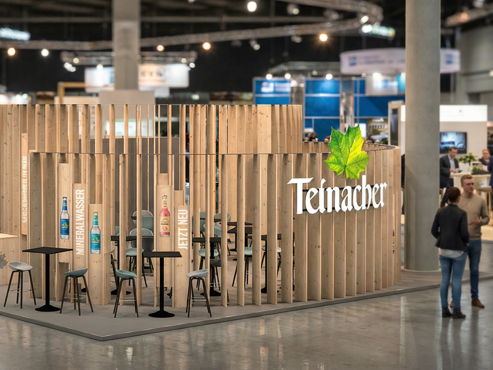 Moderner Teinacher-Messestand aus Holz mit Sitzbereichen und Produktpräsentation in einer Messehalle