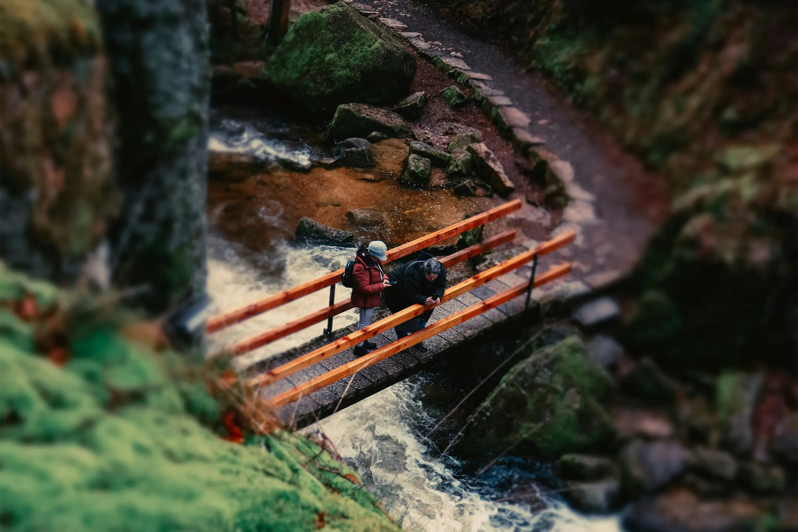 Zwei Personen auf einer Holzbrücke über einem Bach im wildromantischen Murgtal im Schwarzwald
