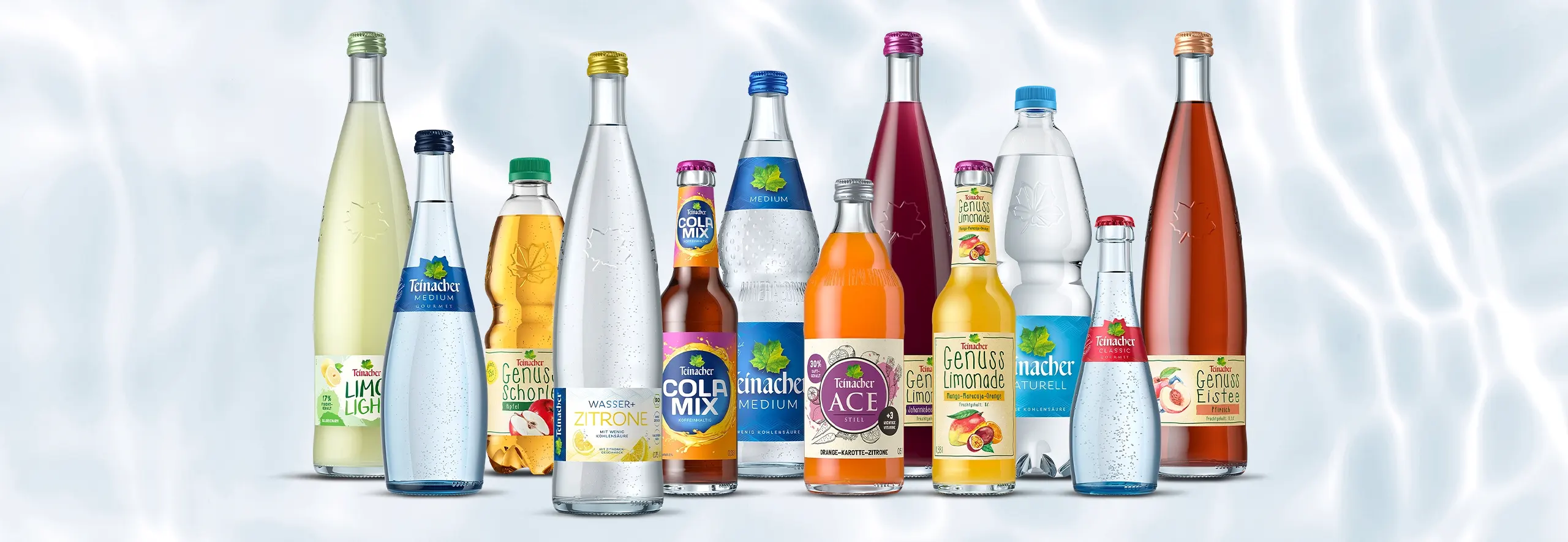 Teinacher Produktsortiment mit Mineralwasser, Limonaden, Schorlen, Cola-Mix und Eistee vor hellem Wasserhintergrund