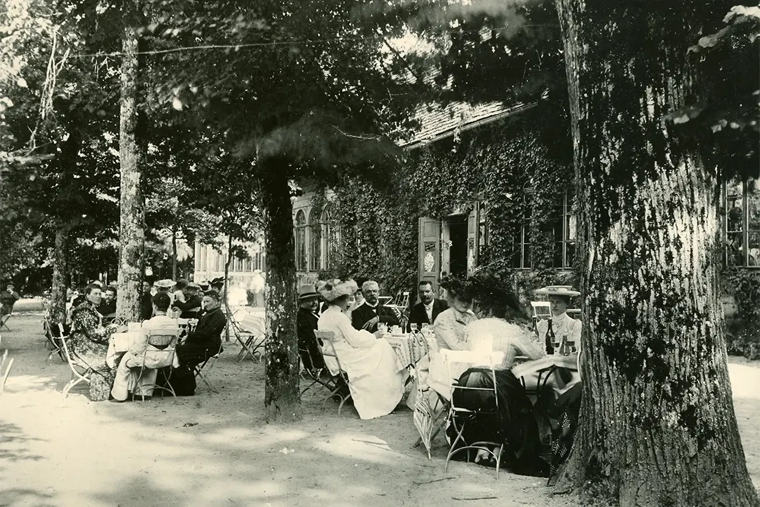Schwarz-Weiß Foto von 1927: Menschen sitzen im Garten eines Lokals und trinken Limonade