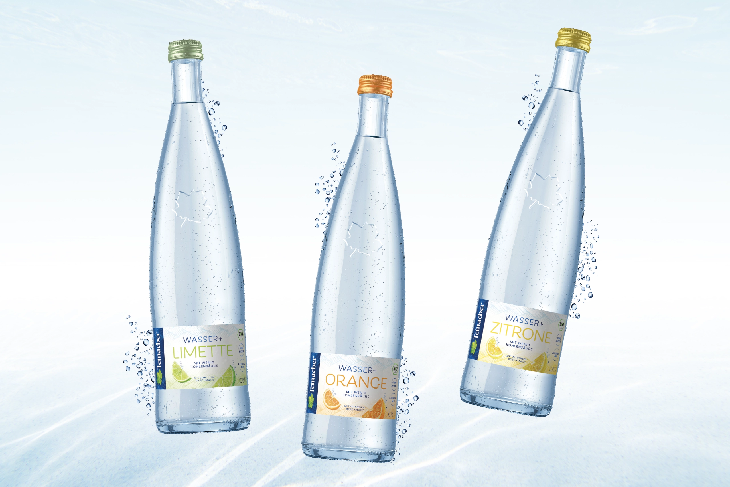 Drei Teinacher Genussflaschen Wasser+ Limette, Orange und Zitrone mit Spritzwasser vor hellem Hintergrund in schwebender Darstellung