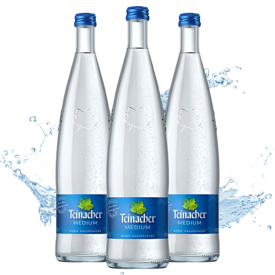 Drei Teinacher Mineralwasser Medium Genussflaschen 0,75 L mit Wasserspritzer im Hintergrund