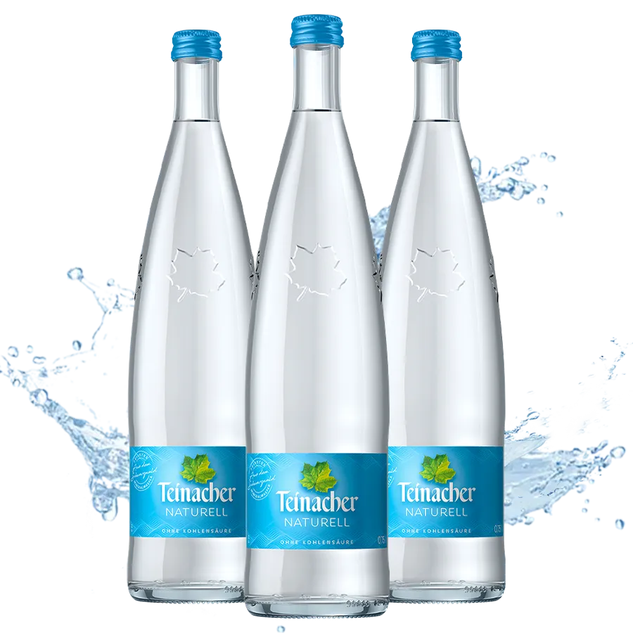 Drei Teinacher Mineralwasser Naturell Genussflaschen 0,75 L mit Wasserspritzer im Hintergrund