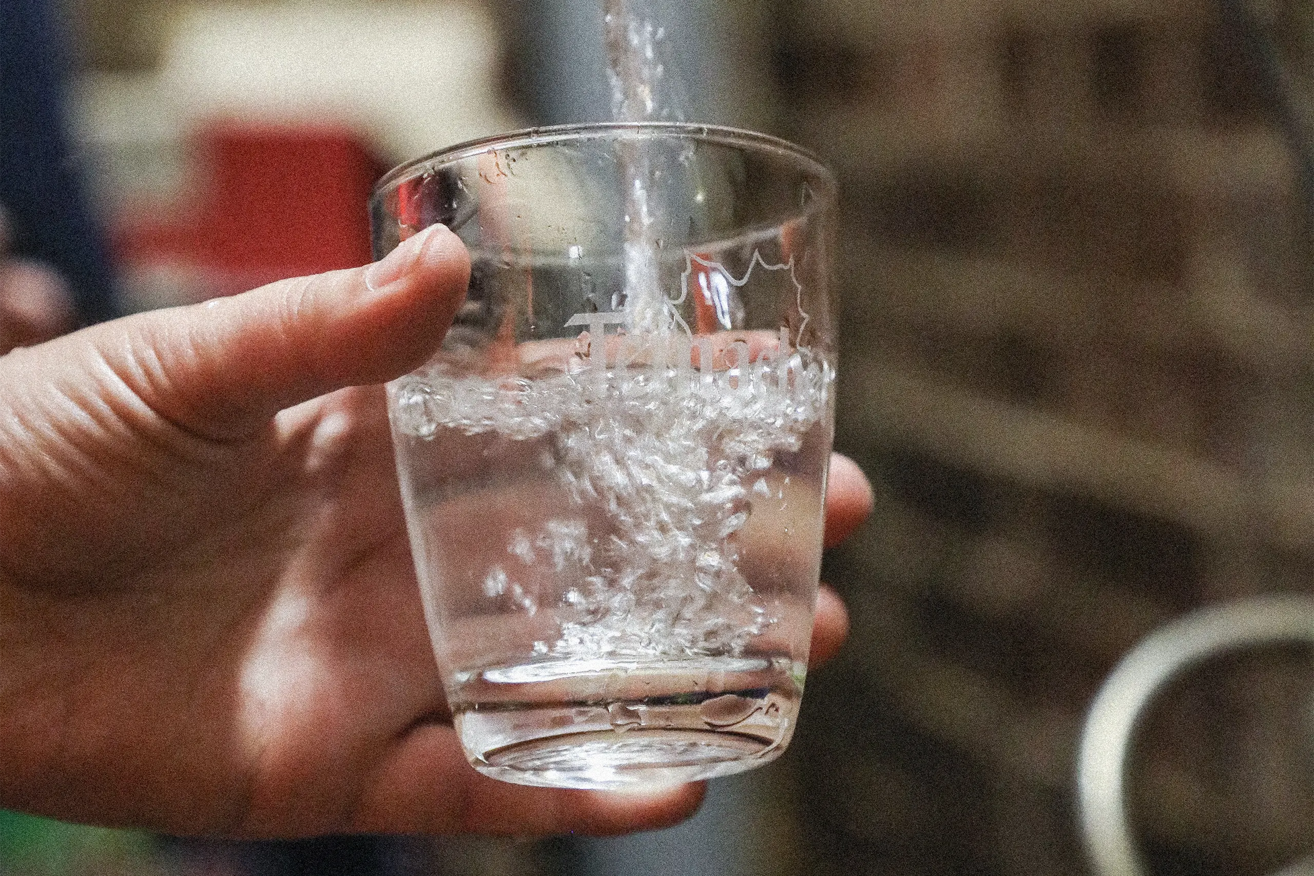 Ein Glas mit Teinacher Logo darauf in das Teinacher Mineralwasser eingefüllt wird.