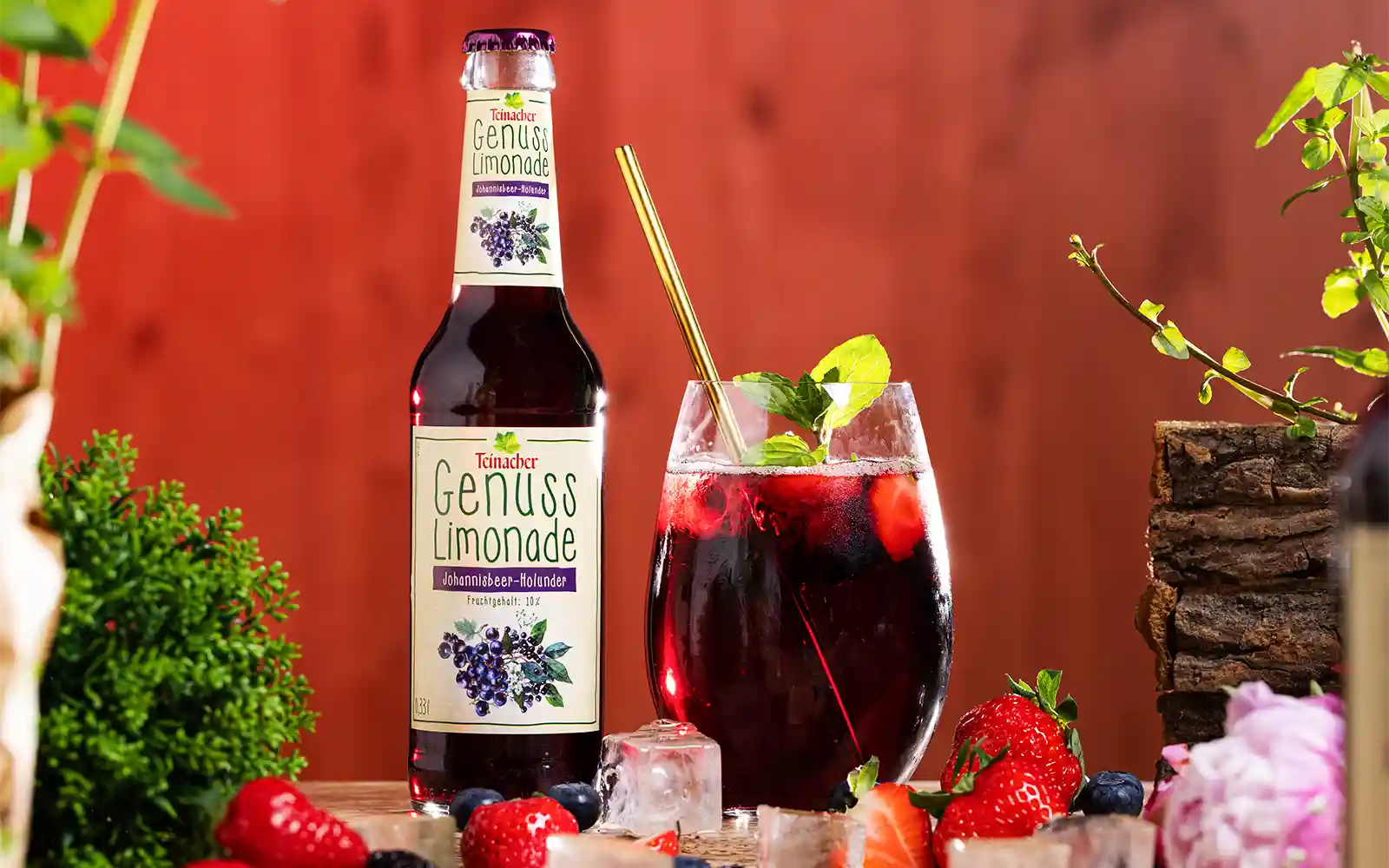 teinacher-rezepte-cocktail-berry-twist-mit-033-liter-genuss-limonade-johannisbeer-holunder Flasche Teinacher Genusslimonade Johannisbeer-Holunder neben einem Glas mit fruchtigem Getränk und Eiswürfeln.