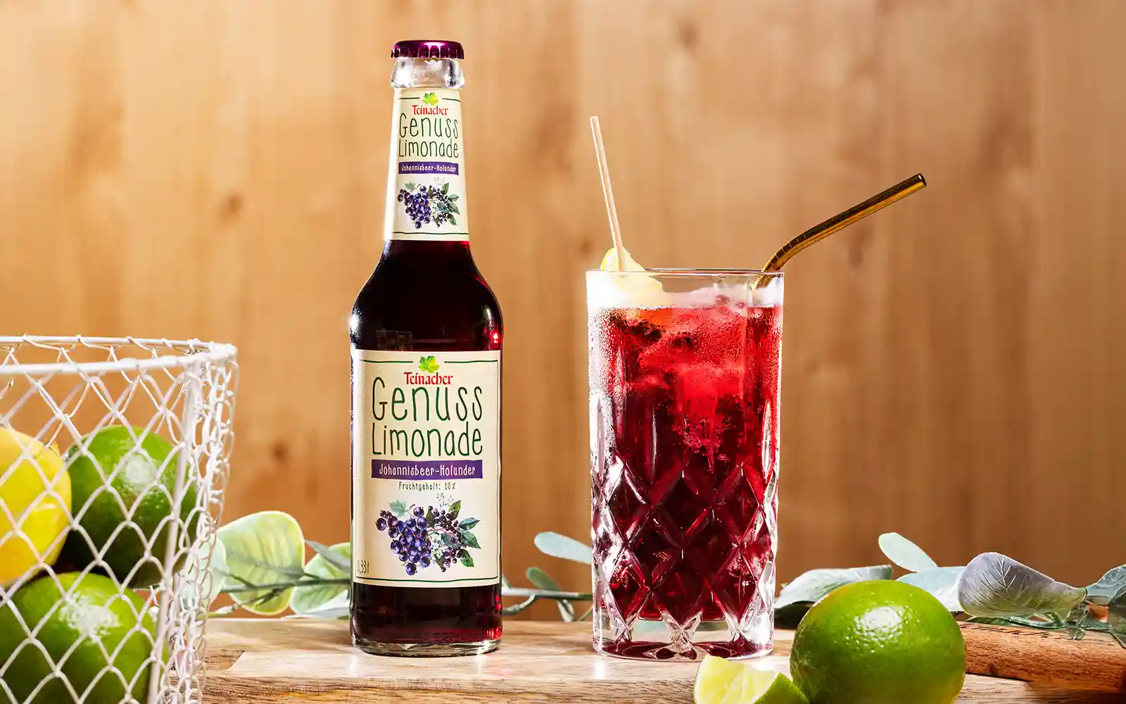 Teinacher Genusslimonade Schwarze Johannisbeere-Holunder Teinacher Genusslimonade Schwarze Johannisbeere-Holunder mit Glas, Limetten und Trinkhalm.