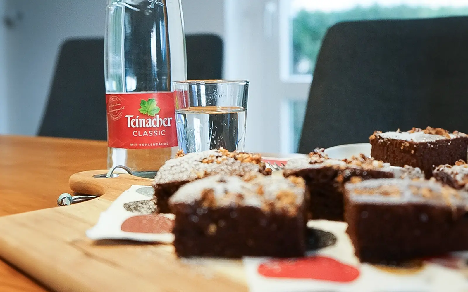 Vorderansicht einem Stück Schokokuchen auf einem Tisch mit einer 0,75 Liter Genussflasche im Hintergrund