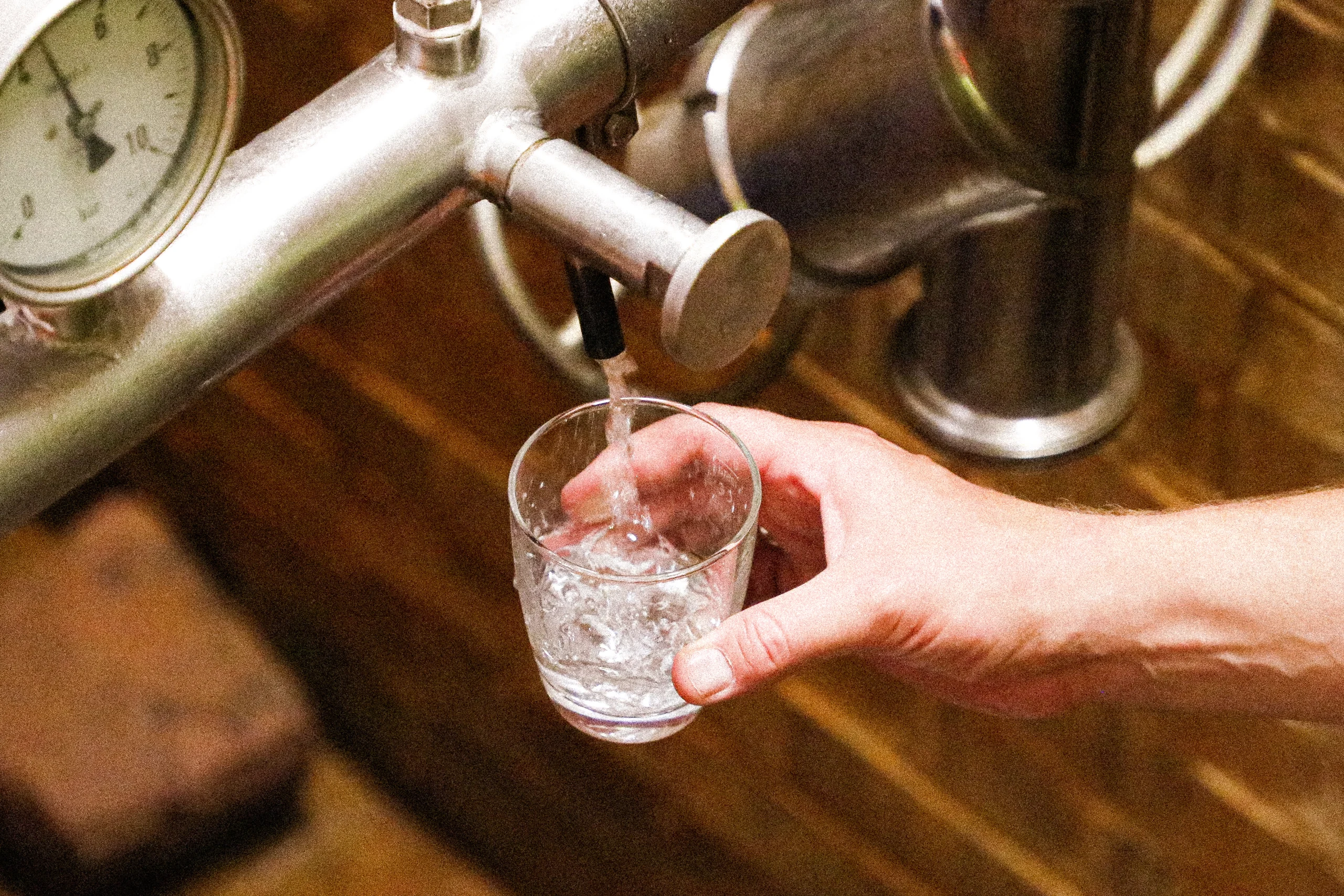 Teinacher Wasser wird aus einem Wasserhahn aus der Quelle in ein Teinacher Glas abgefüllt