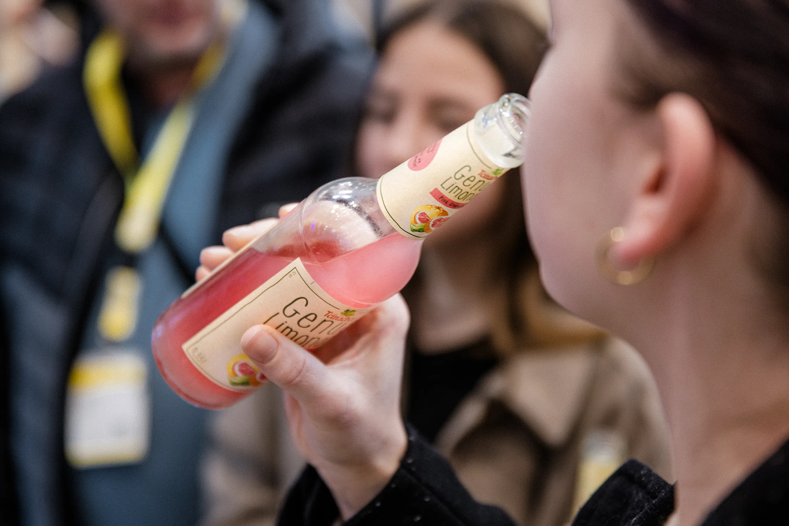 Person trinkt Teinacher Genuss-Limonade Pink Grapefruit aus 0,33 l Longneckflasche in geselliger Situation