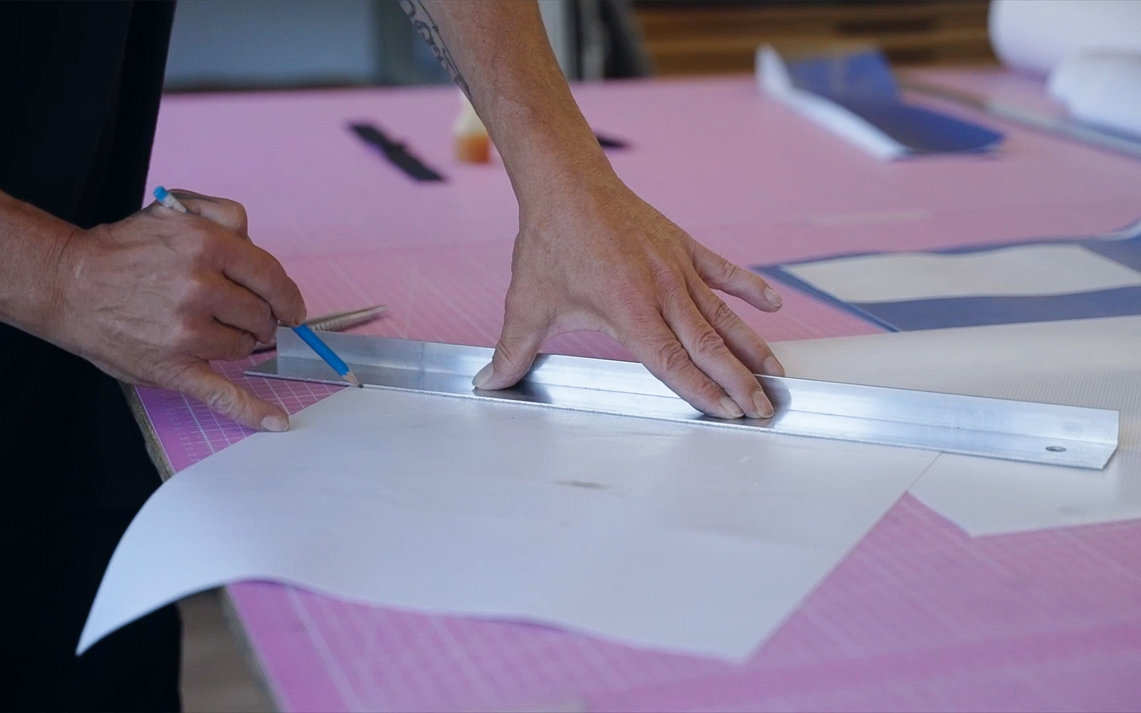 Hände schneiden und markieren Schablonen auf Plakatmaterial mit Lineal und Stift bei der Entwicklung einer Tasche aus Teinacher-Werbeplane