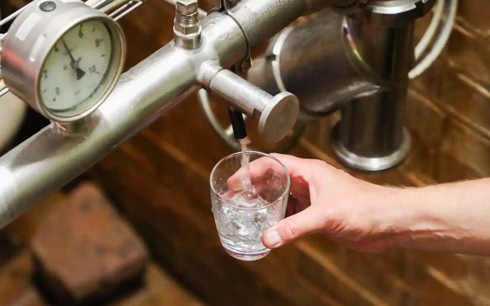 teinacher-wissenswert-wasser-brunnenhaus Frisches Quellwasser fließt durch einen gemauerten Wasserkanal im Inneren einer Brunnenanlage.