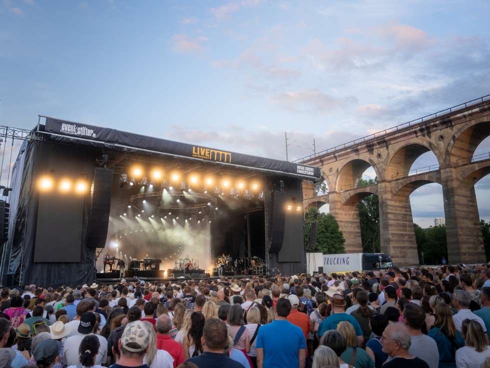 Konzertbühne und Publikum beim Event „Live am Viadukt“ vor historischem Eisenbahnviadukt in Abendstimmung