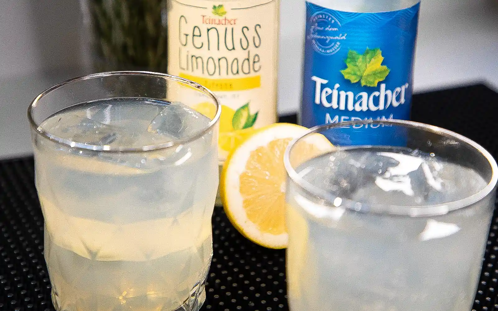 Teinacher Longneck Flaschen mineralwasser Medium und Genuss-Limonade Zitrone mit 2 Gläsern gefüllt mit Eiswürfeln