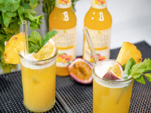 Teinacher Longneck Flaschen Genuss-Limonade Mango-Maracuja-Orange mit 2 Gläsern gefüllt mit Eiswürfeln und Früchten